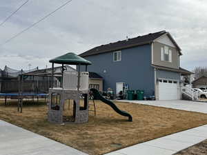 View of jungle gym with a trampoline and a yard