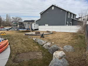 View of yard featuring a trampoline, a fire pit, and a playground