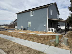 View of home's exterior with a yard, covered porch, and central air condition unit