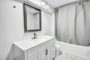 Full bathroom with shower / bathtub combination with curtain, vanity, and toilet