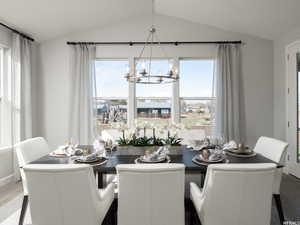 Dining room with lofted ceiling, hardwood / wood-style floors, and an inviting chandelier