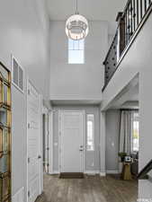 Foyer with a high ceiling, dark wood-type flooring, and an inviting chandelier