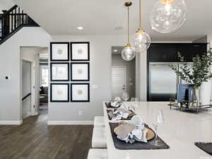 Kitchen with dark hardwood / wood-style flooring, decorative light fixtures, and stainless steel built in fridge
