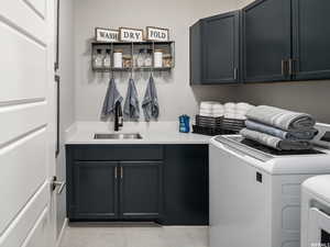 Laundry room featuring separate washer and dryer, sink, and cabinets