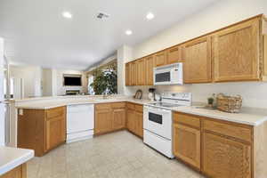 Kitchen with white appliances, kitchen peninsula, and sink