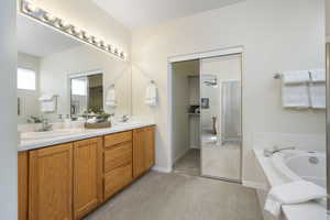 Full bath featuring a garden tub, double vanity, baseboards, and carpet flooring
