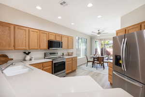 Kitchen with appliances with stainless steel finishes, a sink, light countertops, light wood-style floors, and recessed lighting