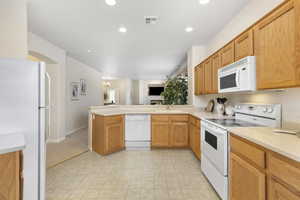 Kitchen featuring sink, white appliances, and kitchen peninsula