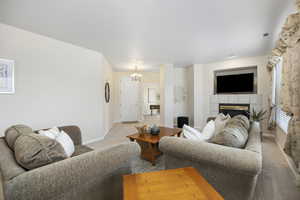 Living room featuring a tiled fireplace, light colored carpet, and a notable chandelier