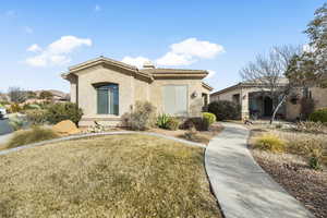 View of front facade with stucco siding, a front lawn, and a tiled roof