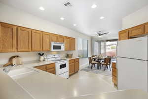 Kitchen featuring sink, white appliances, light tile patterned floors, and ceiling fan