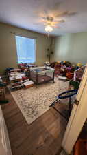 Bedroom featuring ceiling fan, wood-type flooring, and a textured ceiling