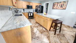 Kitchen featuring a kitchen island, appliances with stainless steel finishes, sink, decorative backsplash, and light stone counters