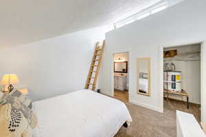 Carpeted bedroom with ensuite bath, a spacious closet, a textured ceiling, electric water heater, and a closet