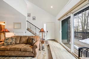 Living room with high vaulted ceiling and light hardwood / wood-style flooring