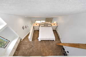 Bedroom with dark carpet, a baseboard radiator, and a textured ceiling