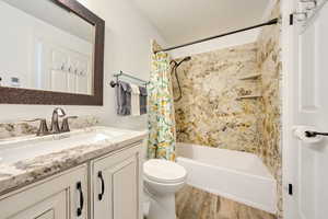 Full bathroom with vanity, toilet, hardwood / wood-style floors, and shower / bath combo with shower curtain