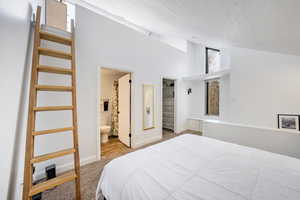 Carpeted bedroom featuring connected bathroom, high vaulted ceiling, and a textured ceiling