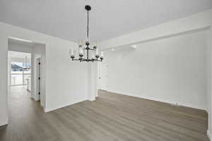 Unfurnished dining area with hardwood / wood-style floors and a notable chandelier