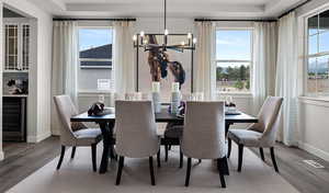 Dining room featuring an inviting chandelier, a healthy amount of sunlight, beverage cooler, and wood-type flooring