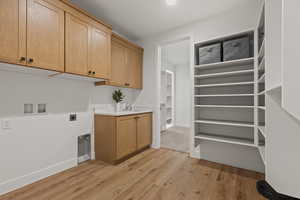 Laundry room featuring sink, cabinets, light wood-type flooring, washer hookup, and hookup for an electric dryer