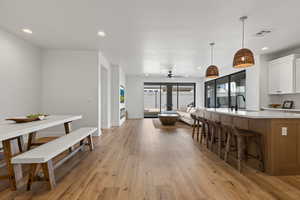 Kitchen featuring sink, ceiling fan, hanging light fixtures, light hardwood / wood-style floors, and white cabinets