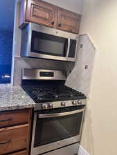 Kitchen with stainless steel appliances, stone counters, and backsplash