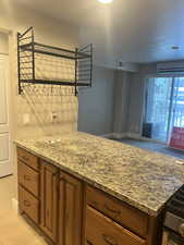 Kitchen with light tile patterned floors, stainless steel stove, a wall mounted AC, a textured ceiling, and stone countertops