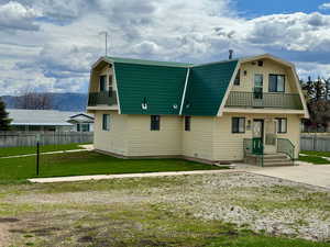 Rear view of property with a mountain view, a lawn, and a balcony