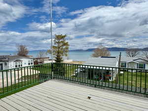 Wooden deck with a water and mountain view and a lawn