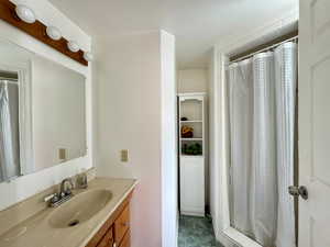 Bathroom in garage featuring vanity, toilet, and walk in shower