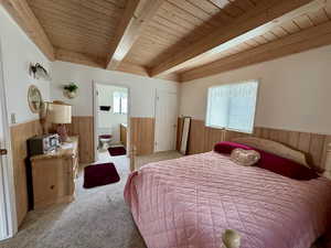 Owner Suite featuring multiple windows, wood ceiling, beam ceiling, and wood walls