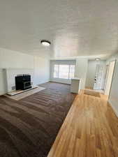 Unfurnished living room featuring hardwood / wood-style flooring and a textured ceiling