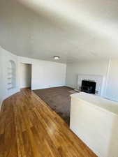 Unfurnished living room with hardwood / wood-style floors, built in features, and a textured ceiling