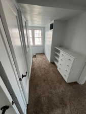 Unfurnished bedroom with dark colored carpet and a textured ceiling