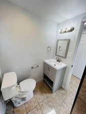 Bathroom with vanity, a textured ceiling, and toilet