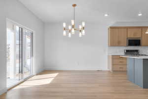 Kitchen featuring backsplash, stainless steel microwave, range, and light wood finished floors