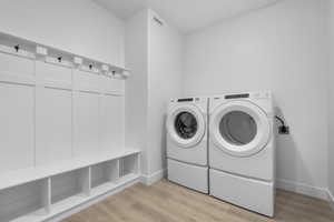 Clothes washing area featuring washer and clothes dryer and light hardwood / wood-style floors