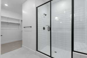 Bathroom with a shower stall, tile patterned floors, baseboards, and a spacious closet