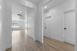 Corridor with visible vents, baseboards, recessed lighting, and wood finished floors