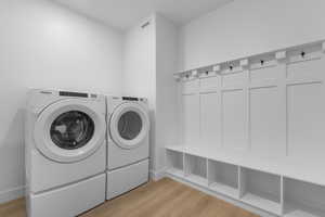 Laundry room with washer and dryer, laundry area, and light wood finished floors