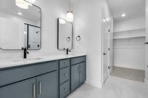 Bathroom featuring a walk in closet, double vanity, a sink, and a stall shower