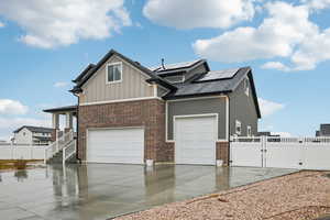 View of side of property featuring a garage and solar panels