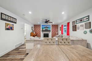 Living room with wood-type flooring, a large fireplace, and ceiling fan