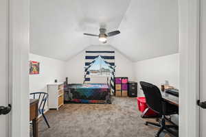 Carpeted bedroom featuring ceiling fan, lofted ceiling, and a textured ceiling