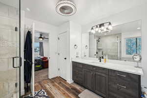 Bathroom featuring a shower with door, wood-type flooring, vanity, and ceiling fan