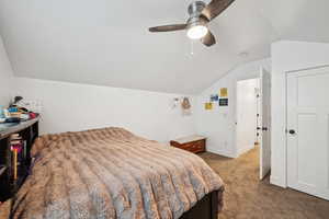 Carpeted bedroom with ceiling fan and vaulted ceiling