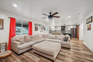 Living room featuring a barn door, hardwood / wood-style floors, and ceiling fan