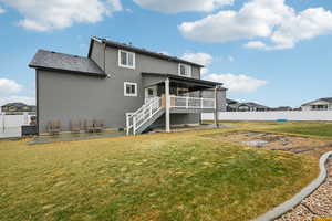 Back of property with a wooden deck and a yard