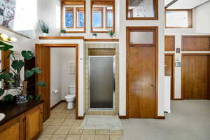 Bathroom with vanity, toilet, a shower with shower door, and tile patterned flooring